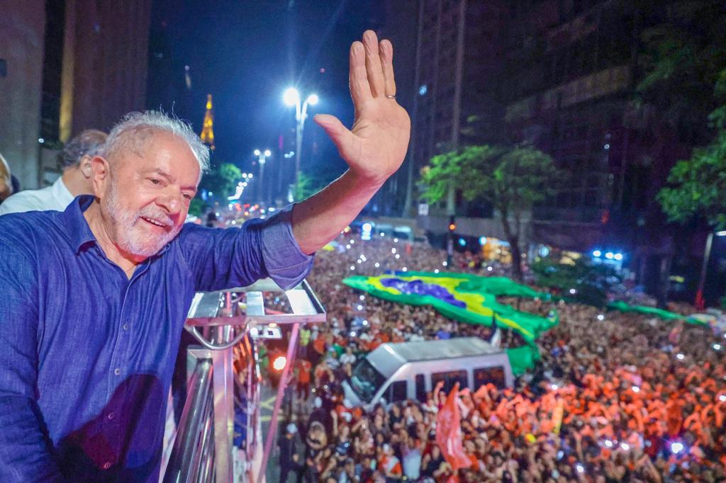Lula acena em vibrante comício noturno para multidão.