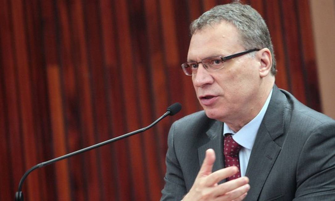 Homem de terno falando ao microfone em evento formal