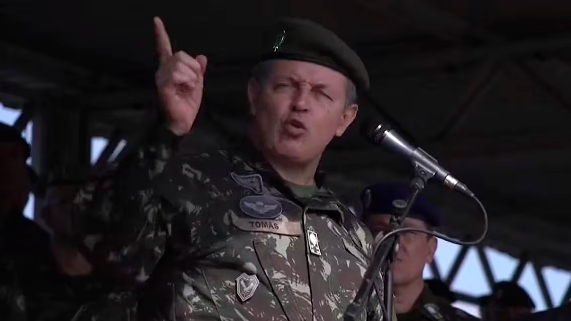 Oficial militar Tomas discursando com veemência e gesto enfático