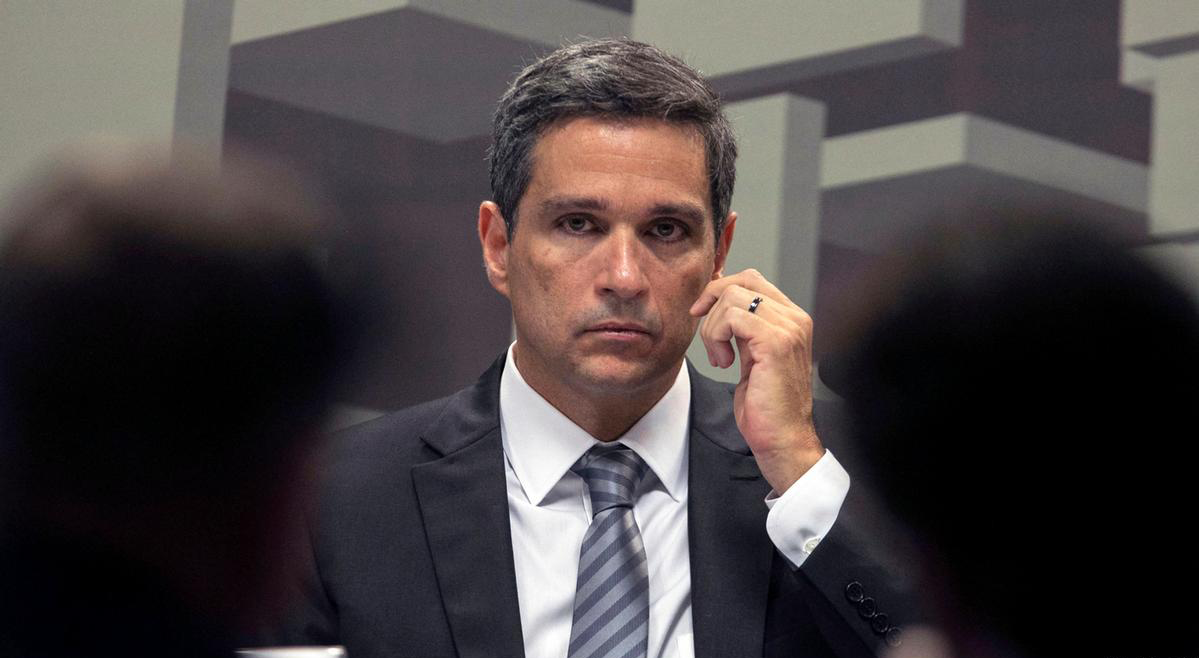 Homem em terno, expressão séria, em ambiente institucional