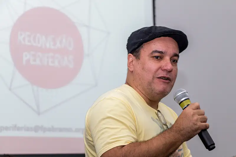 Palestrante em evento "Reconexão Periferias" com microfone