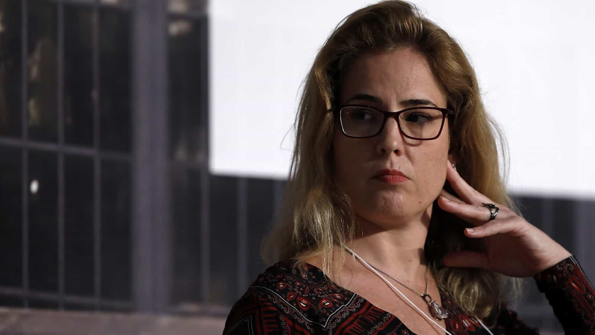 Mulher em reflexão profunda, evento, óculos, expressão séria.