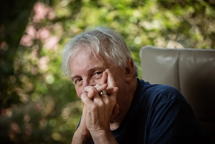 Homem idoso, cabelos grisalhos, olhar direto e pensativo