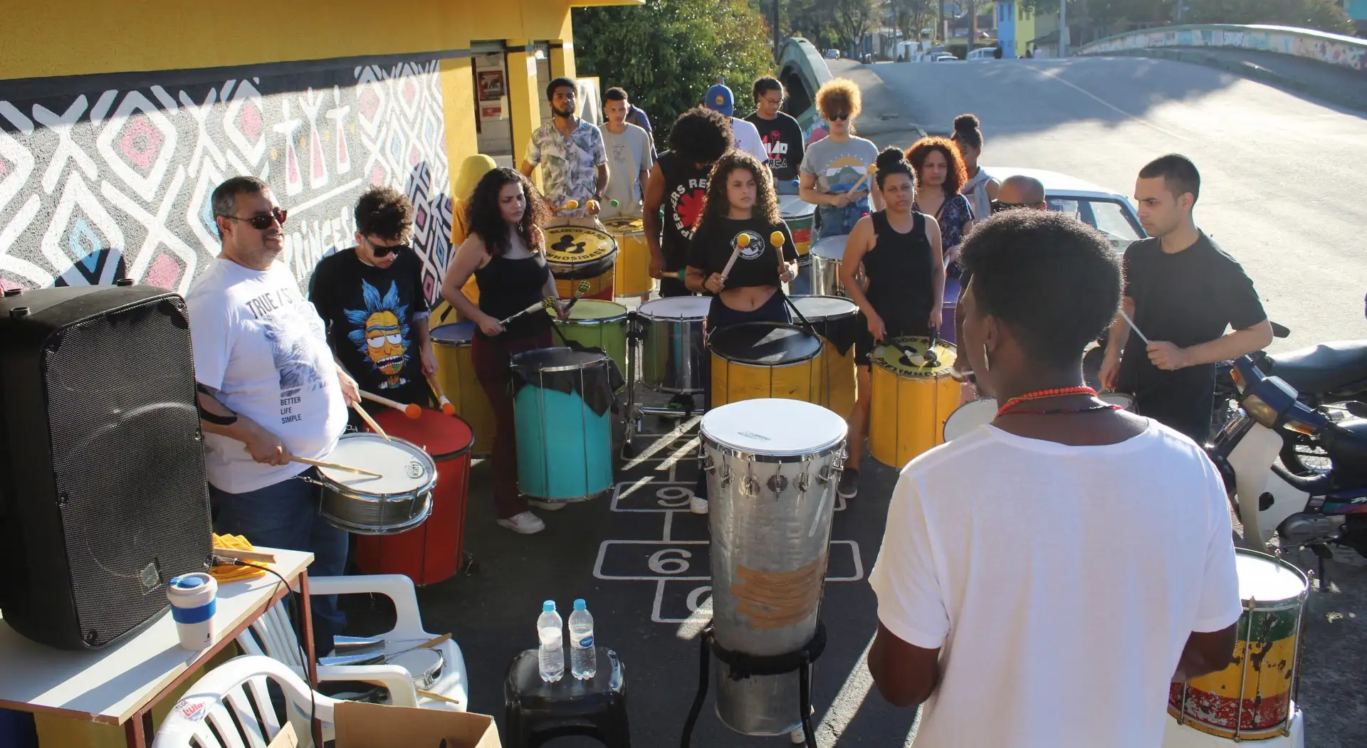 Jovens e Adultos em Oficina de Percussão Comunitária ao Ar Livre.