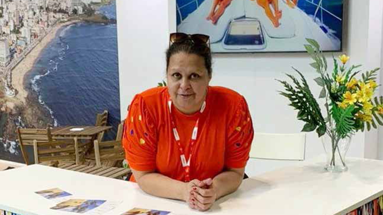 Mulher Sorridente em Estande de Evento de Turismo