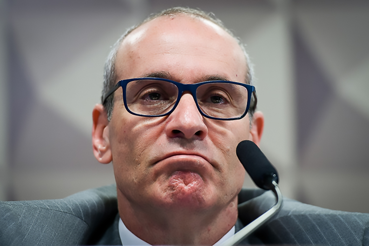 Homem sério com óculos e microfone em debate