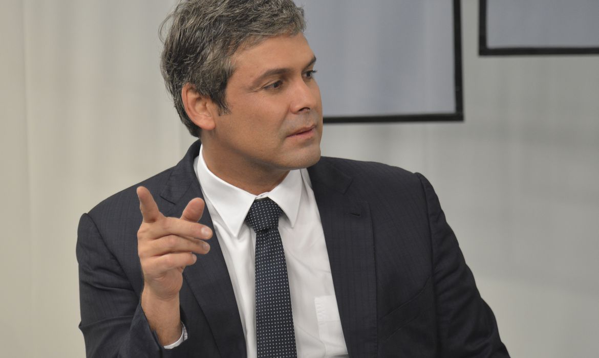 Homem em terno, gesto firme, em discussão focada.