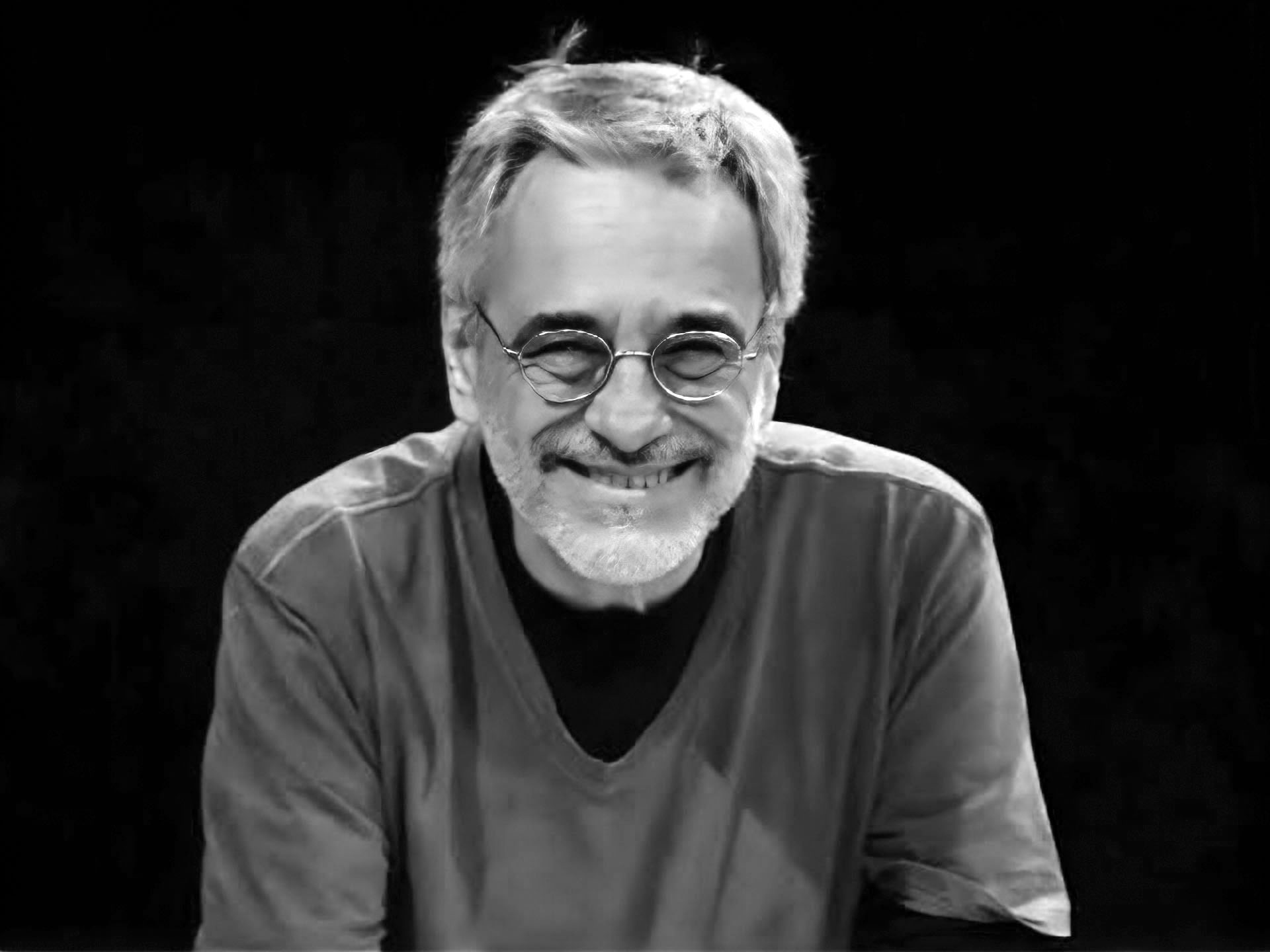 Retrato de homem sorridente, óculos, barba grisalha, P&B.