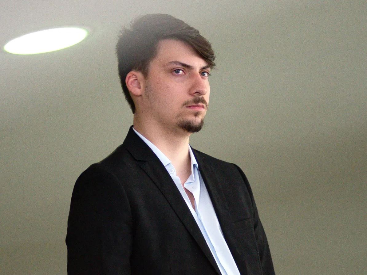 Homem jovem pensativo, terno preto, olhar sério