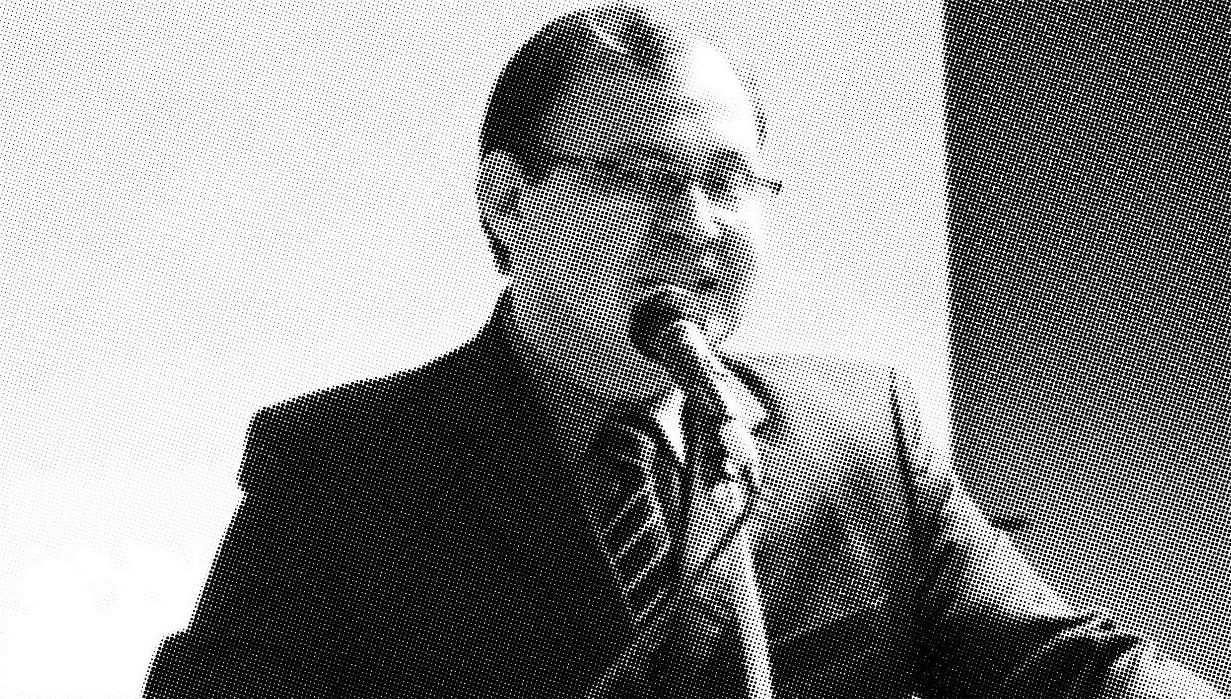 Homem em terno discursa ao microfone em preto e branco