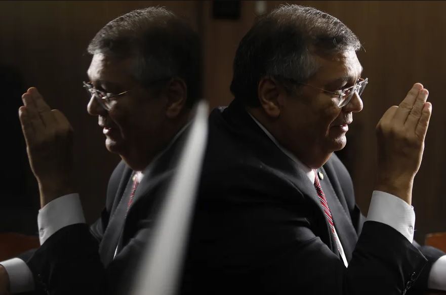 Homem em Terno Gesticula com seu Reflexo