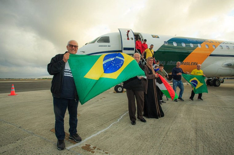 Brasileiros e Palestinos celebram retorno com bandeiras no aeroporto.