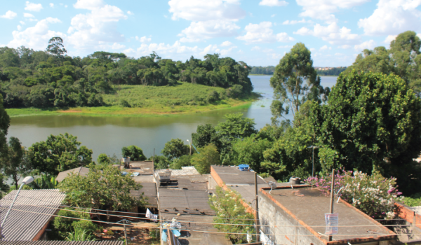 Vista de casas, lagoa e floresta em área periférica
