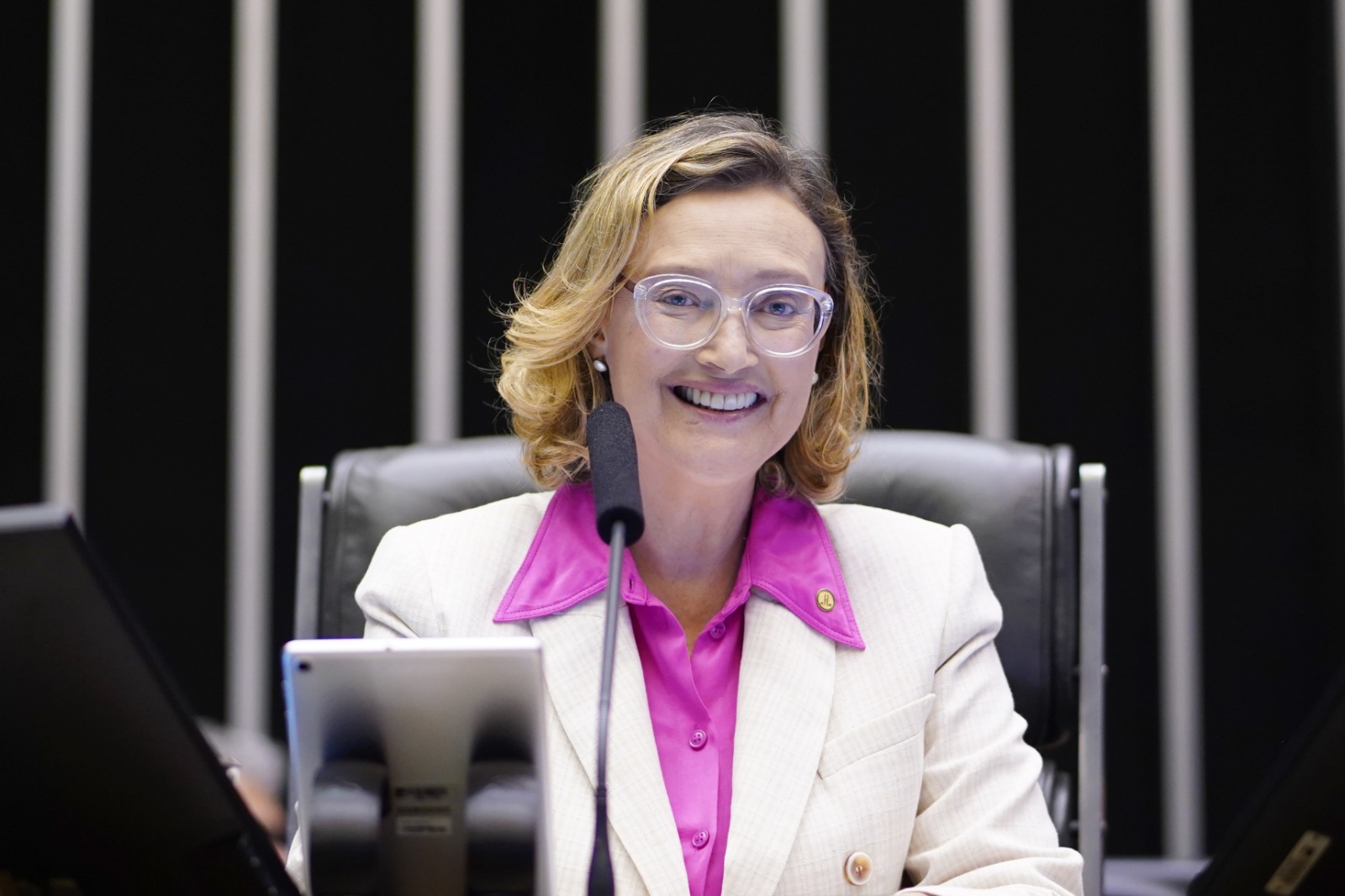 Mulher sorrindo em sessão legislativa: Liderança e otimismo