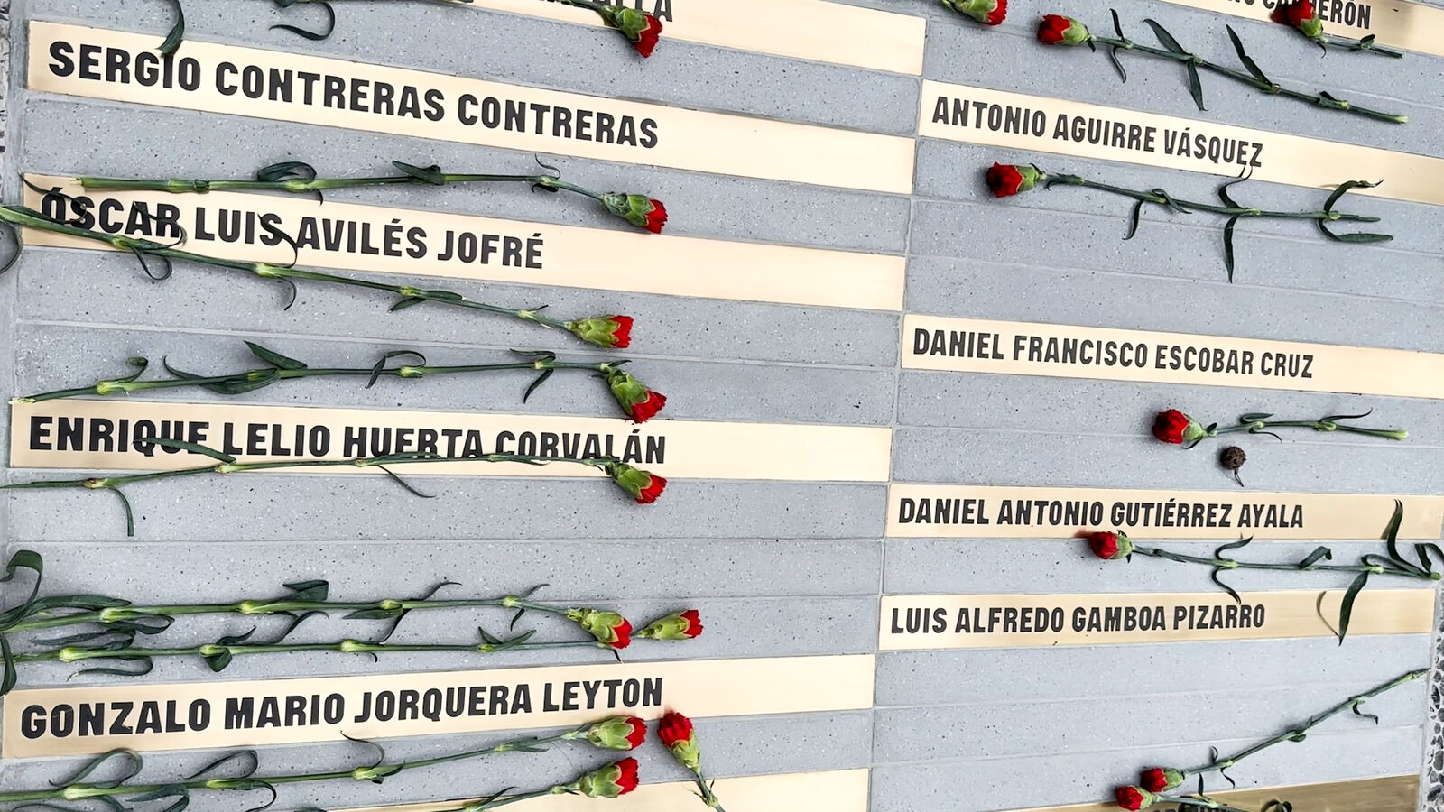 Memorial com nomes e cravos vermelhos: memória e tributo.