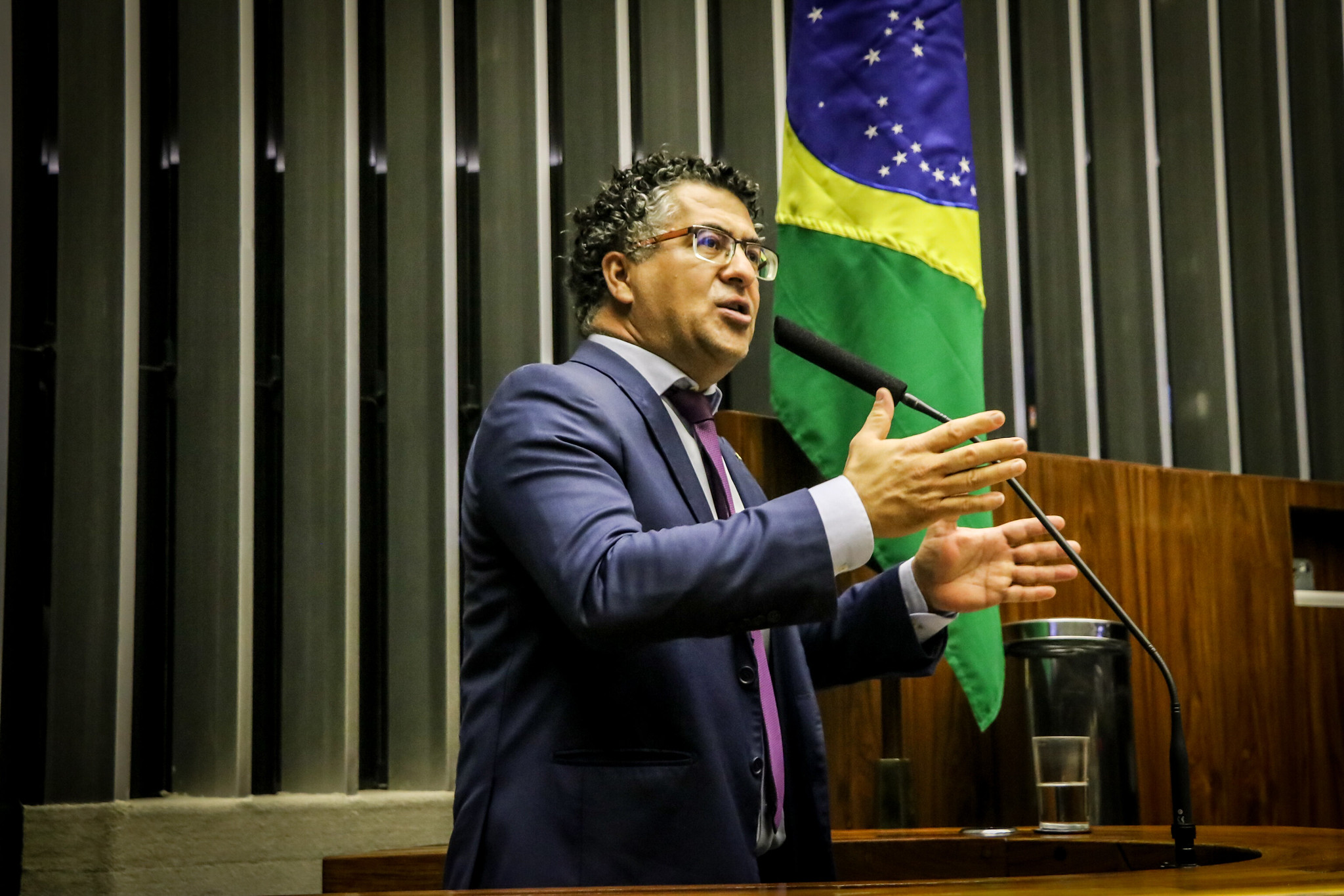 Político discursando no Congresso Nacional com bandeira do Brasil