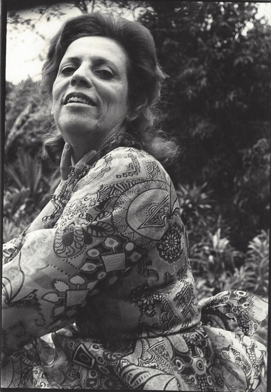 Mulher sorridente com blusa estampada em jardim (preto e branco)