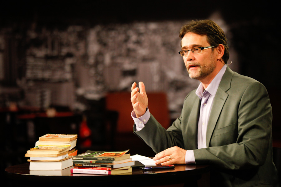 Debate Intelectual: Palestrante Gesticulando com Livros