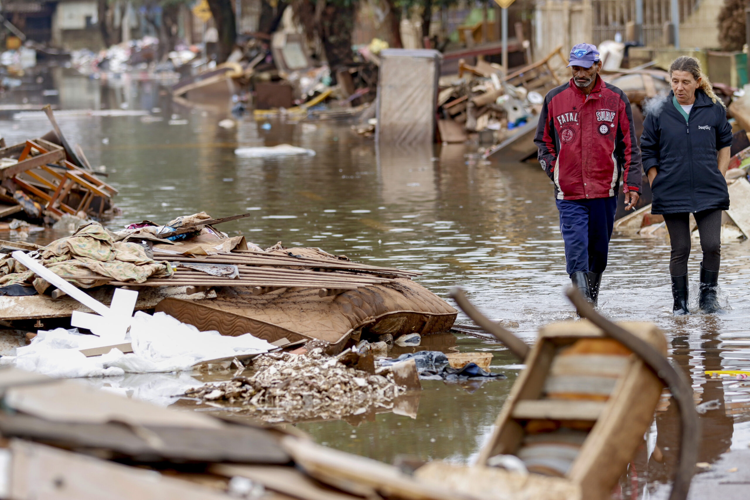 Pessoas Caminham Pela Enchente em Meio à Destruição