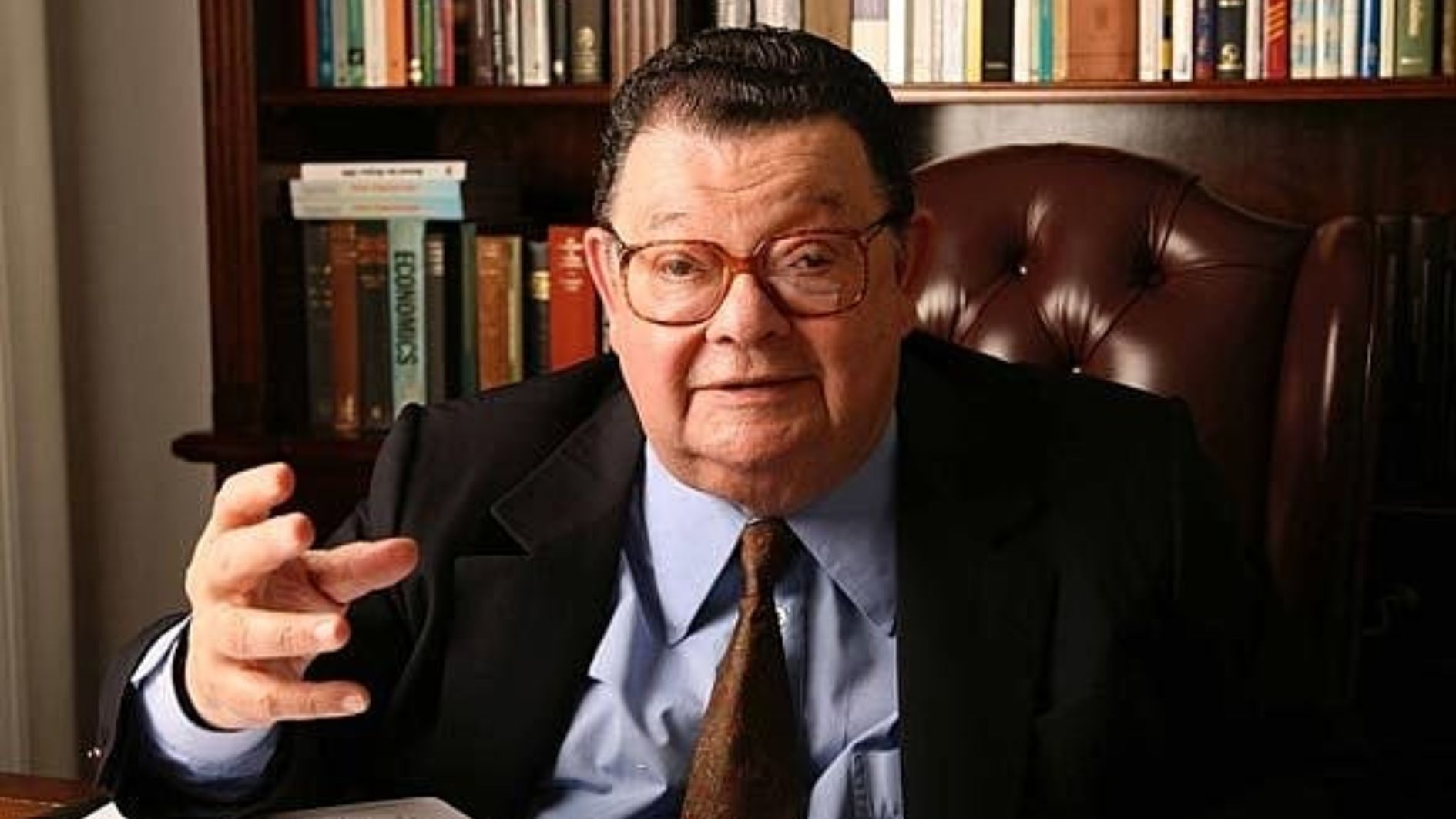 Retrato de homem em escritório com livros de Economia