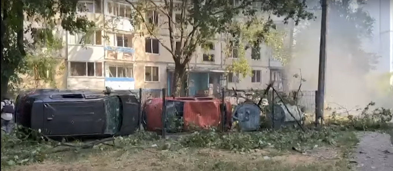 Destruição urbana: carros capotados e edifício abalado.