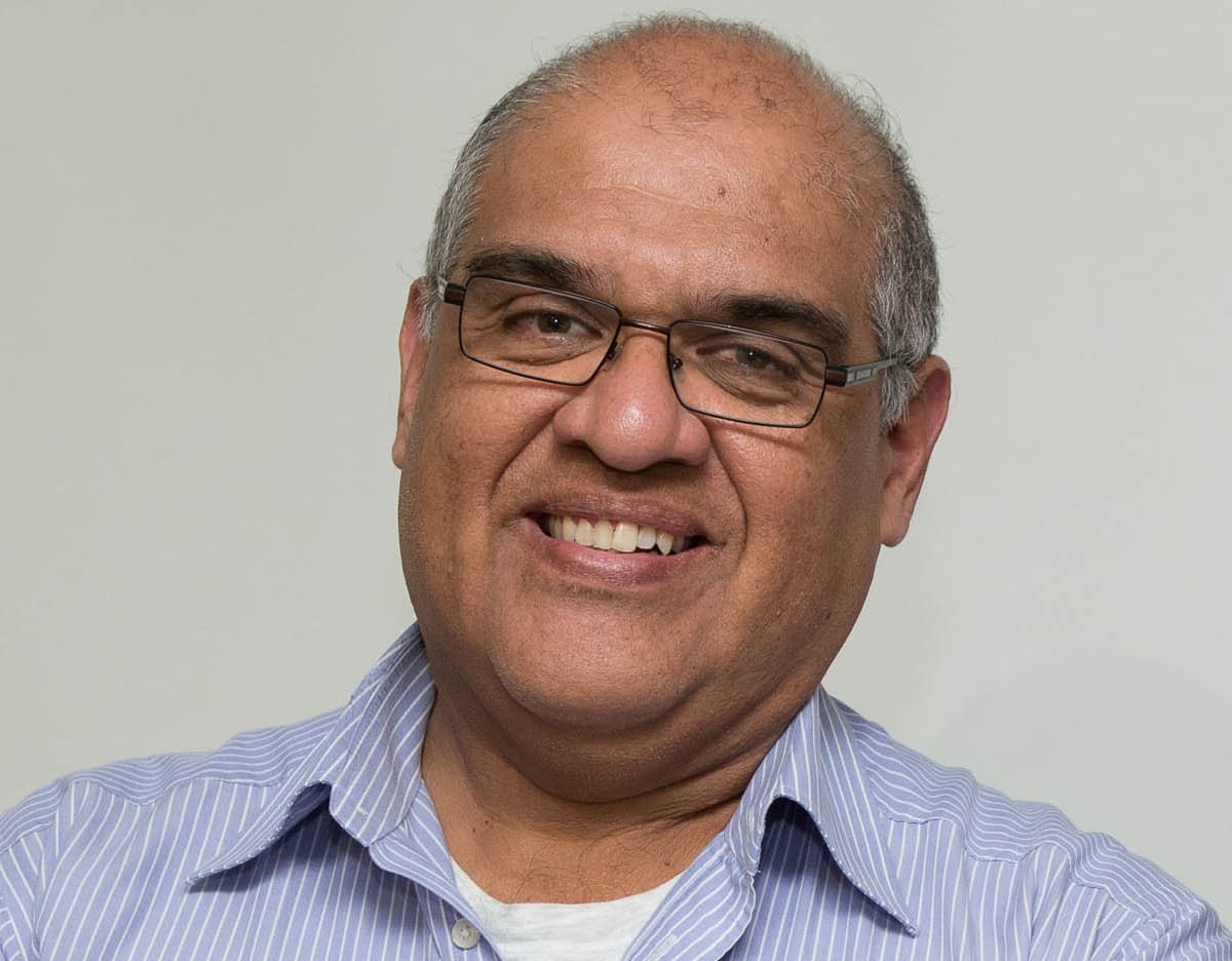 Retrato de homem sorridente de meia-idade com óculos.