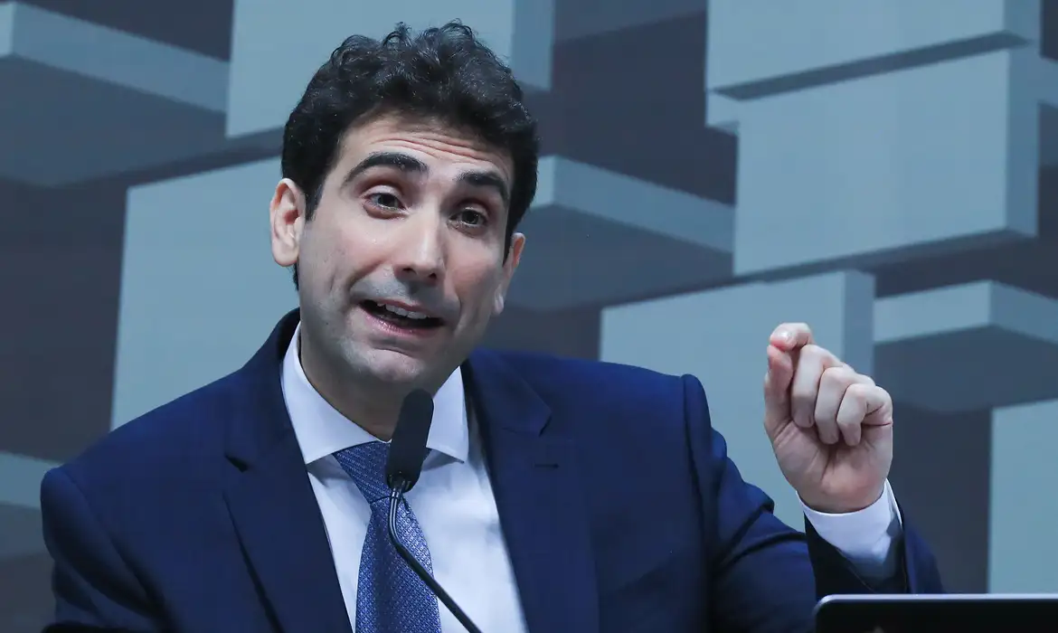 Homem de Terno Azul Discursa em Cenário Institucional