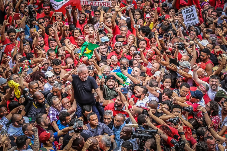 Lula em comício vibrante, aclamado por multidão de apoiadores.