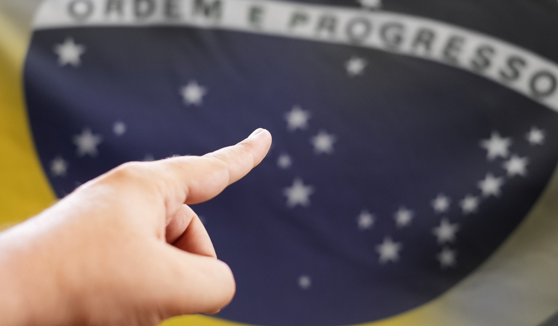 Mão Apontando a Bandeira do Brasil: Direção e Reflexão