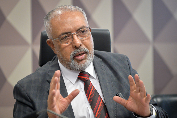 Homem barbudo de terno gesticula ao falar