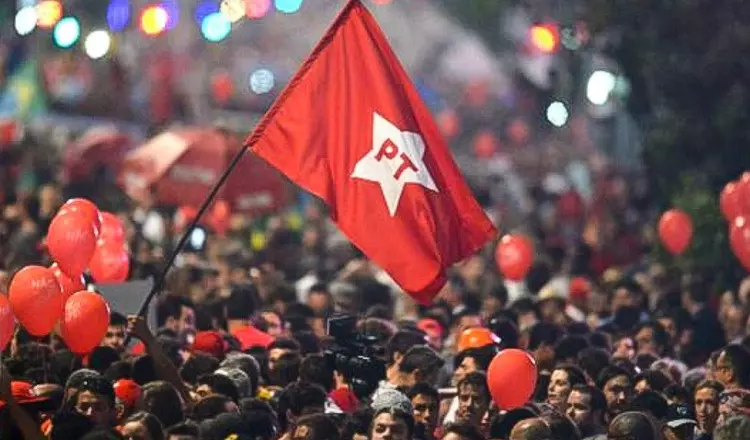 Multidão em manifestação do PT com bandeira e balões vermelhos.