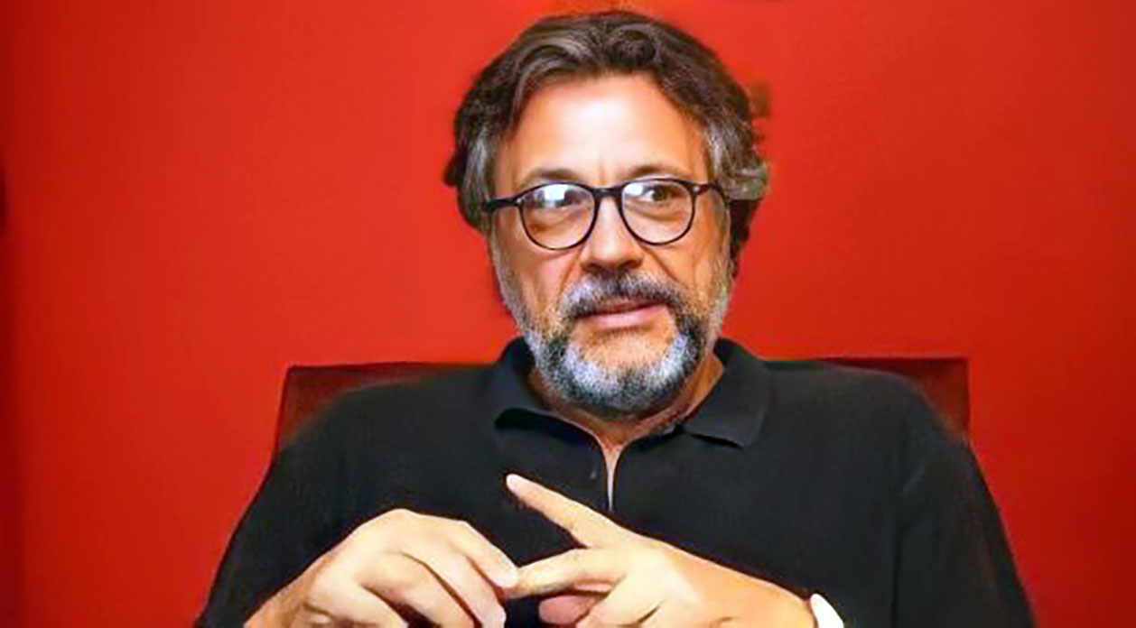 Retrato de homem com barba e óculos em fundo vermelho