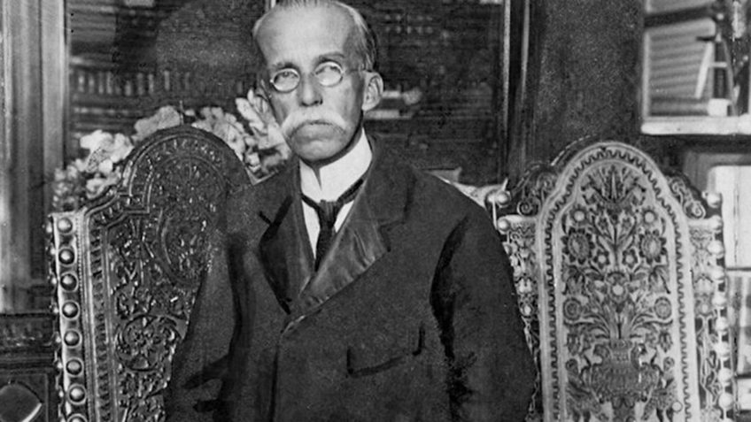 Retrato Histórico: Homem com Óculos e Bigode em Cadeira Entalhada