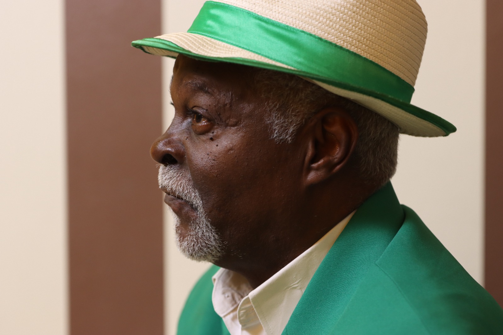 Homem negro de chapéu verde: perfil pensativo e elegante.