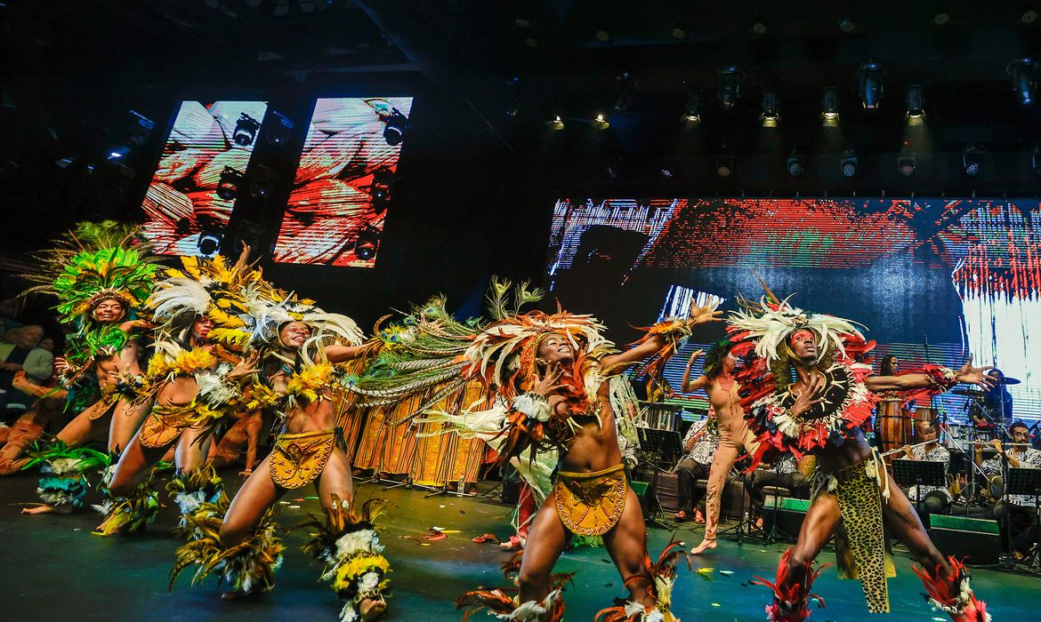 Performance cultural vibrante com dançarinos e figurinos de penas.