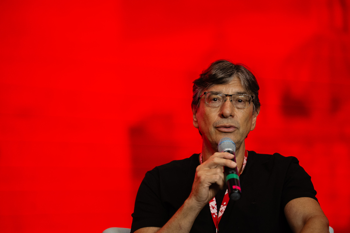 Palestrante com Microfone em Fundo Vermelho