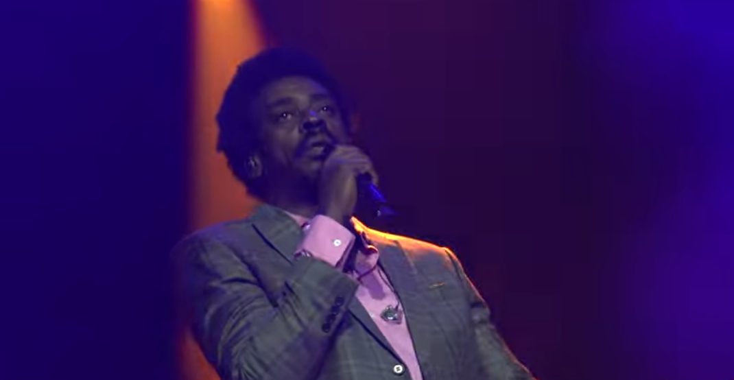 Cantor performando no palco com paixão sob holofotes