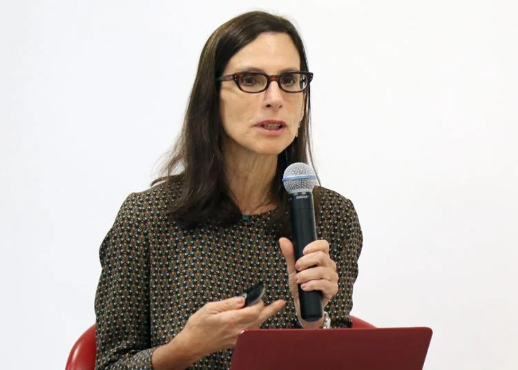 Mulher palestrante de óculos com microfone em evento