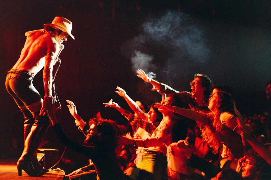 Artista performático no palco interage com público em show vibrante