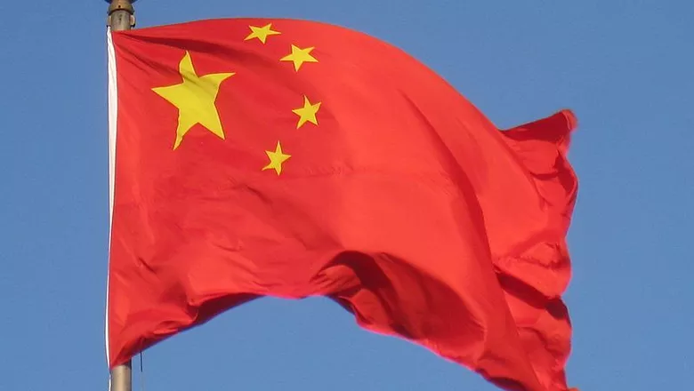 Bandeira da China tremulando ao vento sob céu azul.