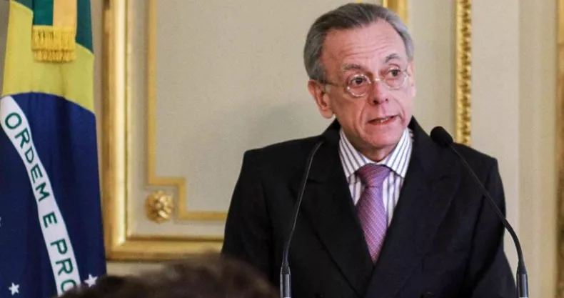 Homem discursando em evento oficial com Bandeira do Brasil