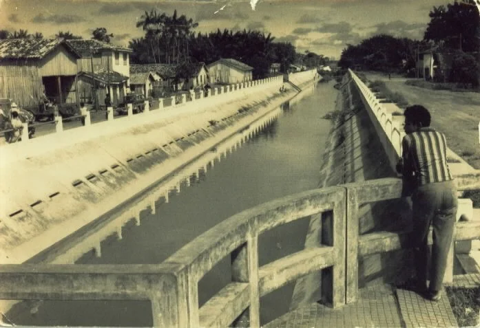 Homem observando canal em área residencial ribeirinha