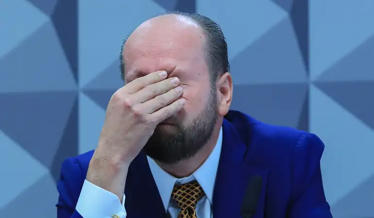 Homem emocionado em público cobrindo os olhos