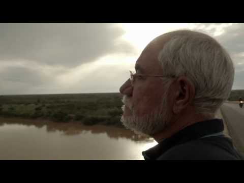 Homem Contempla Rio e Horizonte Sob Nuvens
