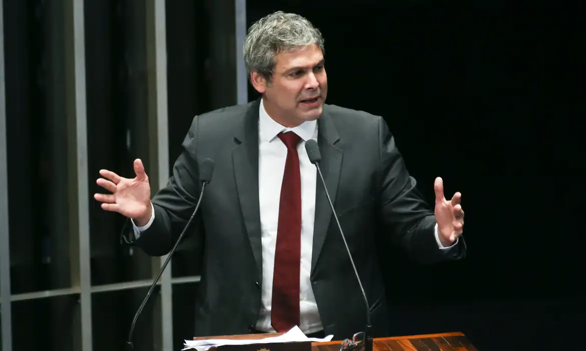 Político discursando em púlpito oficial com gestos.