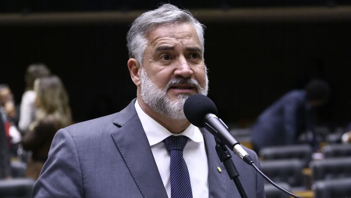 Homem de terno discursando em ambiente legislativo