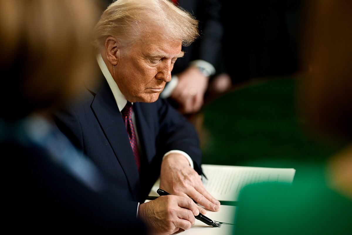 Donald Trump assinando documento oficial em ato presidencial
