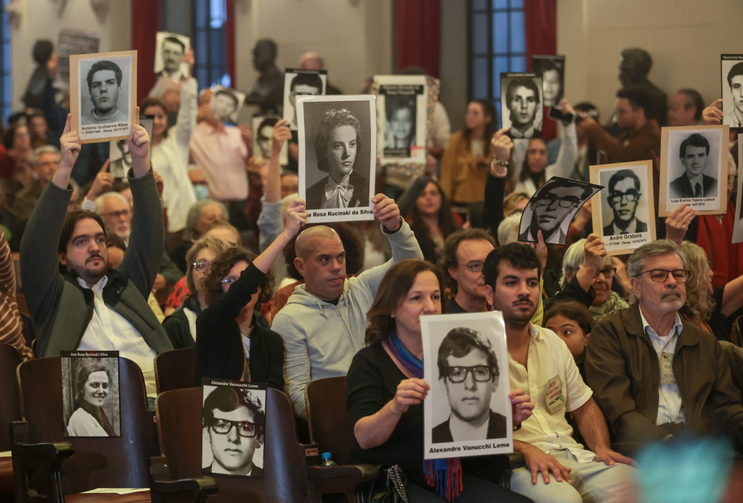 Pessoas lembram vítimas da ditadura com fotos.