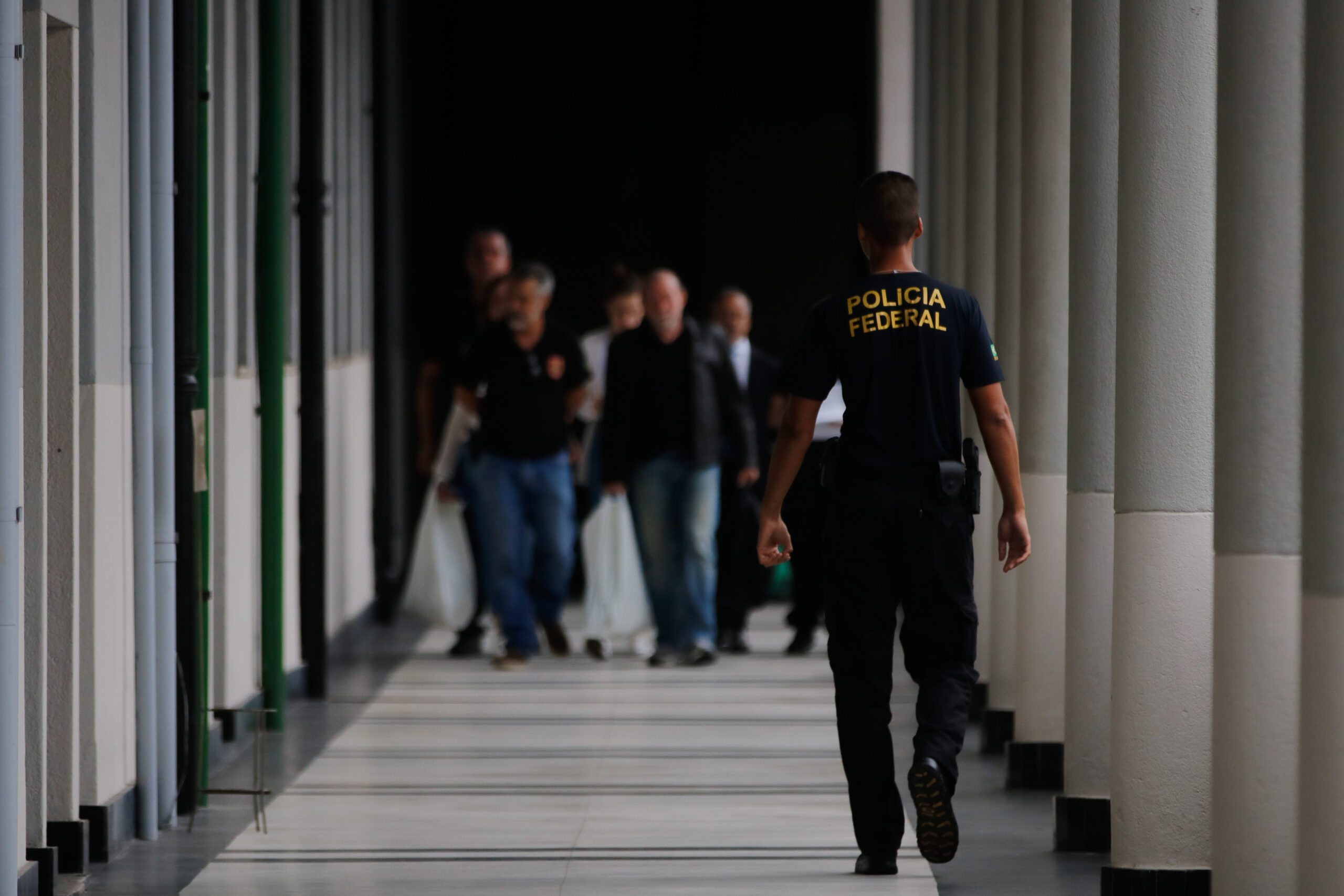 Polícia Federal em Operação: Agente e Civis em Corredor