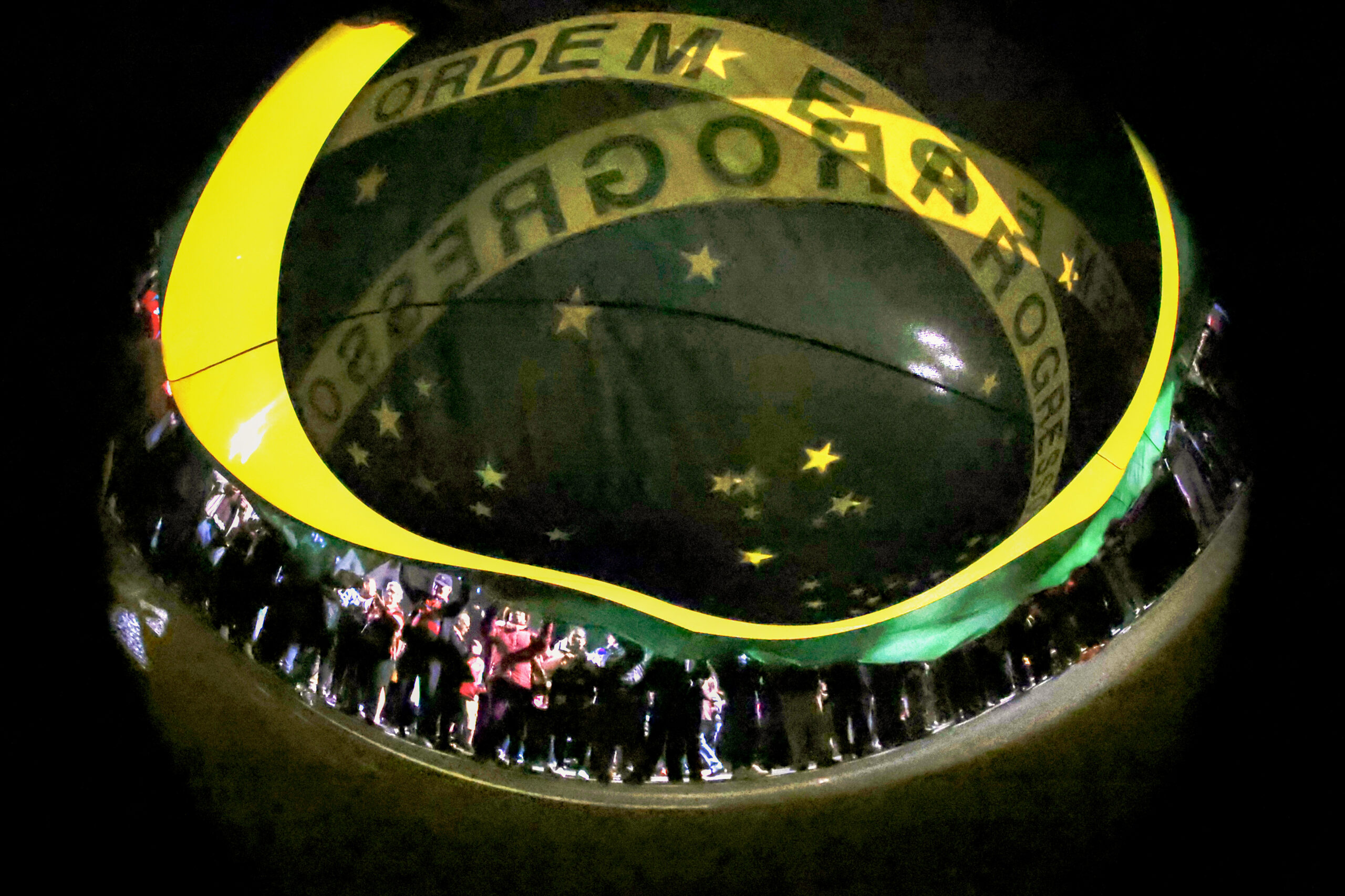 Multidão Noturna Exibe Bandeira do Brasil: Ordem e Progresso